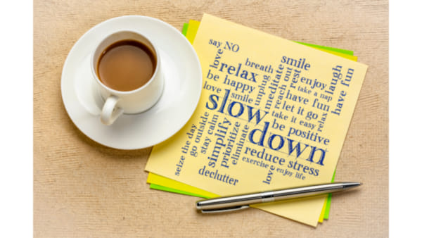 A yellow post it note with ideas for stress management written on it next to a cup of tea