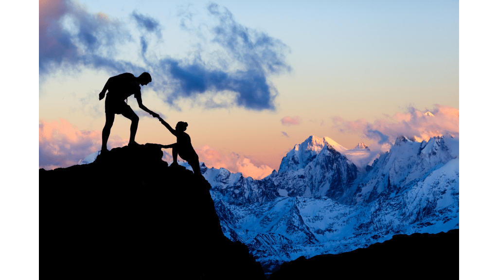 Photo of someone helping their partner climb over a cliff top