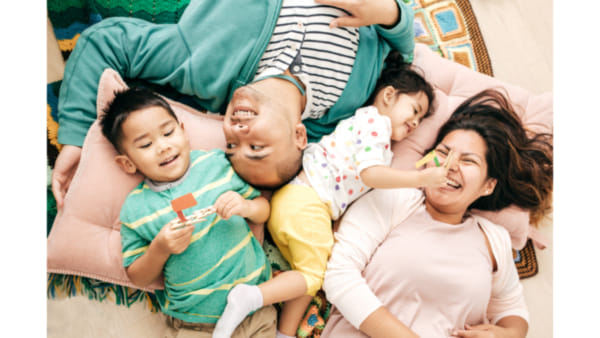 Photo of a married couple with two children laughing together lying on the floor
