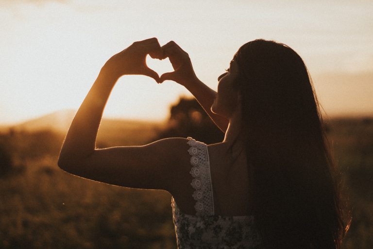 Picture of a woman making a heart out of her hands to represent self-care